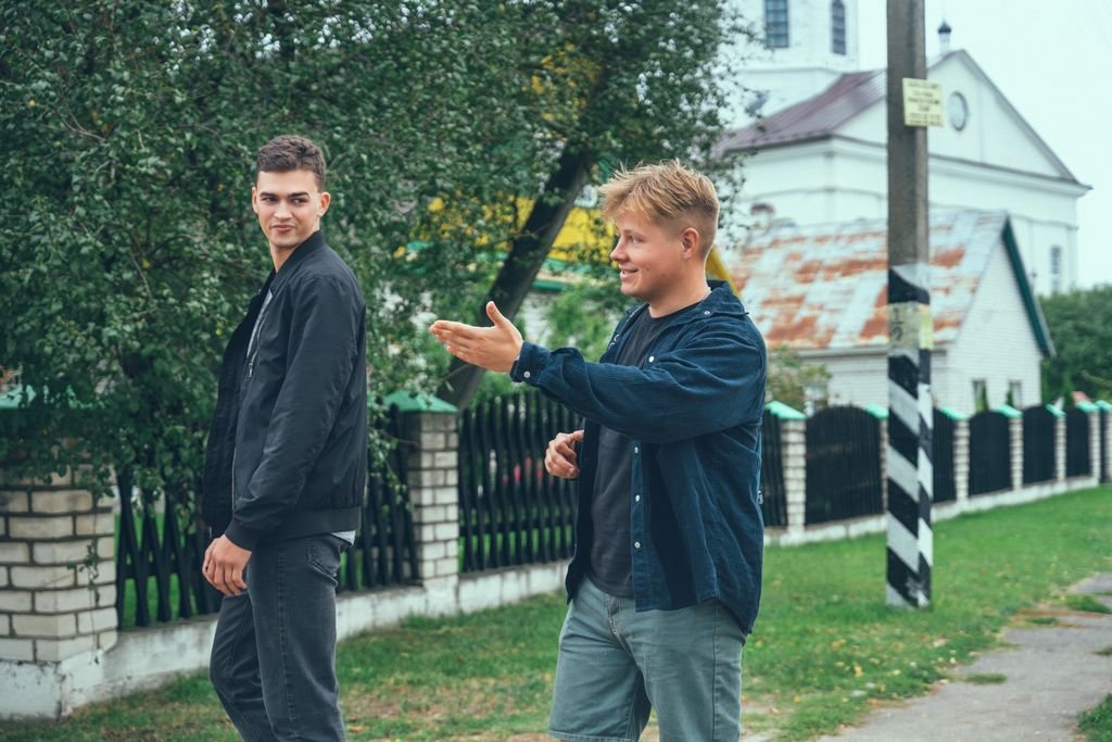 Two young men happily converse while strolling through a serene urban area.