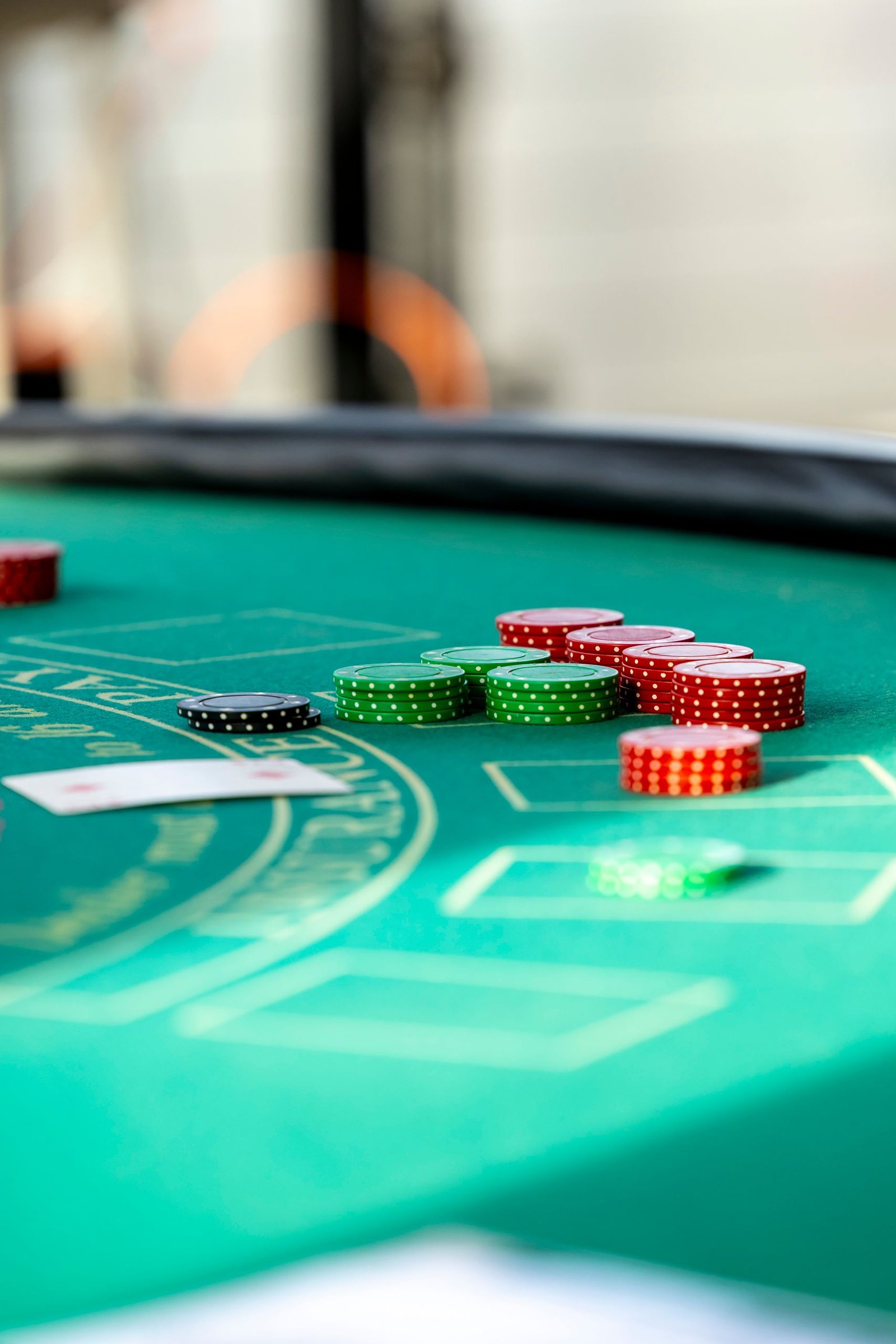A close-up of casino chips and playing cards on a green blackjack table, capturing the excitement of gambling.