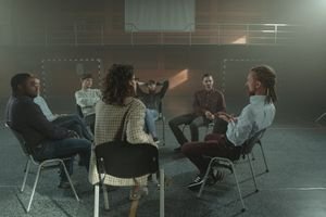 A diverse group engages in a therapy session inside a gym, fostering mental health support.