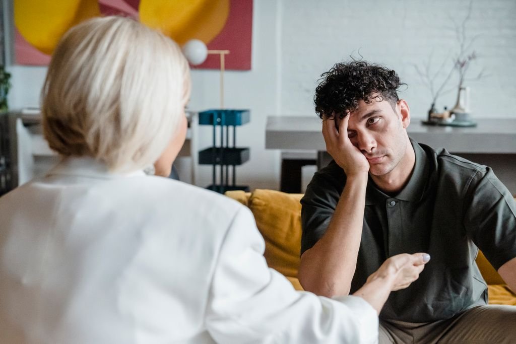 A therapist in session with a young man in a modern, artistic office setting.